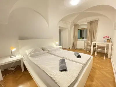 a large white bed in a room with a table at Villa pod Gradom in Ljubljana