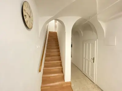 a hallway with a clock on the wall and a staircase at Villa pod Gradom in Ljubljana