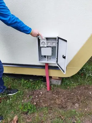 a person is holding a device on the side of a house at Holiday house Hona Lux in Velike Lašče
