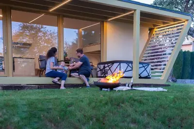 a man and woman sitting on a porch next to a fire at Holiday house Hona Lux in Velike Lašče