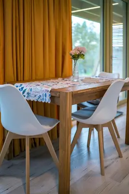 a table with two white chairs and a vase with flowers at Holiday house Hona Lux in Velike Lašče