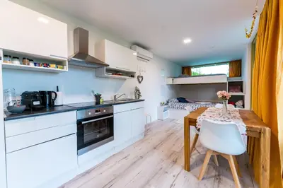 a kitchen with white cabinets and a wooden table at Holiday house Hona Lux in Velike Lašče