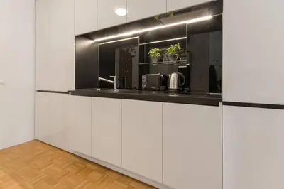 a kitchen with white cabinets and a black counter top at Gorgeous central flat with garage in Ljubljana