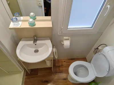 a bathroom with a sink and a toilet and a window at F95 AQUALUNA KAMP NATURA PODČETRTEK swimming card not included in Podčetrtek