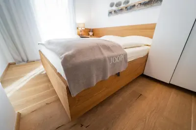 a small bedroom with a bed with a wooden floor at Bor in Bor Luxury Apartment with sauna & garden - Kranjska Gora in Kranjska Gora