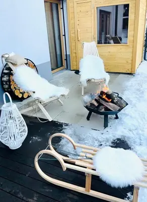 two white chairs sitting on a porch with a fire at Bor in Bor Luxury Apartment with sauna & garden - Kranjska Gora in Kranjska Gora