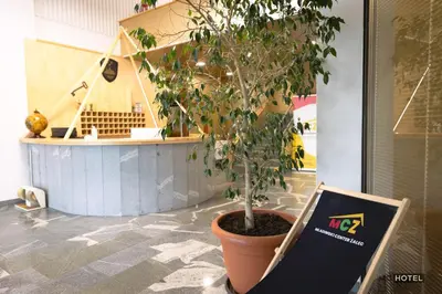 a tree in a pot on a floor with a sign at MC Hotel in Žalec