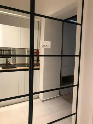 a kitchen with white cabinets and a glass wall at Sunny home with cute dragon in the center+parking in Ljubljana