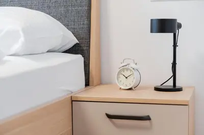 a alarm clock on a nightstand next to a bed at Apartments Naklo in Naklo