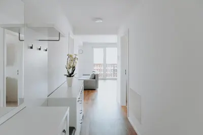 a white kitchen with white cabinets and a couch at Apartments Naklo in Naklo
