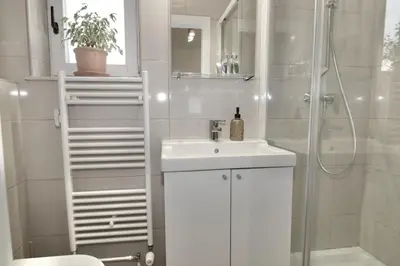 a white bathroom with a sink and a shower at Studio City in Ljubljana