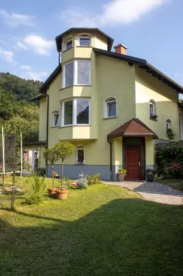 a yellow house with a red door in a yard at Riverside Villa Avo - Apartment Martin in Spodnja Idrija
