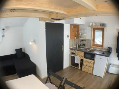 a small kitchen with a black door and a black chair at Tiny house in Mislinja