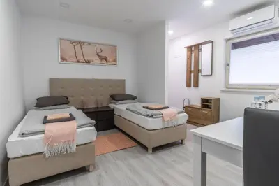 a bedroom with two beds and a desk and a window at Apartments Park Vodice - Ljubljana, Krvavec in Woditz