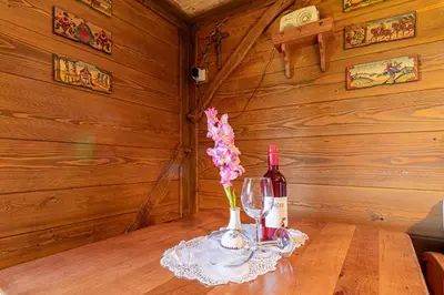 a bottle of wine and a vase of flowers on a table at Holiday home in Otocec - Kranjska Krain 26039 in Otočec