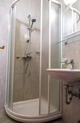 a shower with a glass door next to a sink at LAGOJA b&b in Trzin