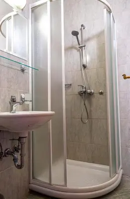 a shower with a glass door next to a sink at LAGOJA b&b in Trzin