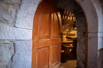 a wooden door in a stone wall with a table at Tourist Farm Škerlj in Dutovlje