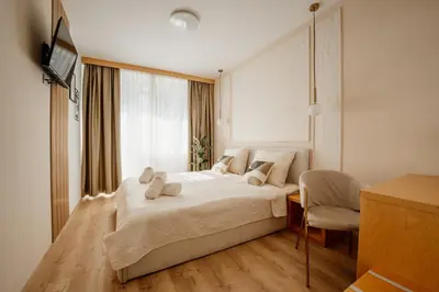a bedroom with a large white bed and a chair at Hotel Jeruzalem in Ljutomer