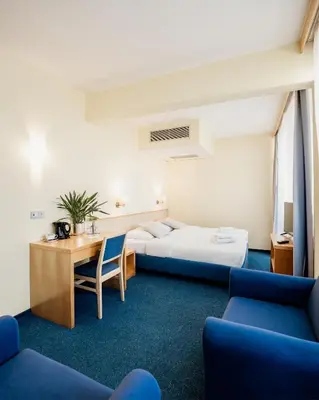 a hotel room with two beds and a table and chairs at Hotel Jeruzalem in Ljutomer