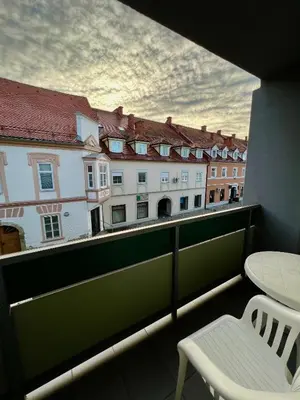 a balcony with a white chair and a view of buildings at Hotel Jeruzalem in Ljutomer