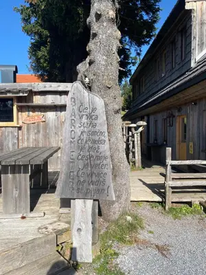 a stone sign sitting next to a tree at Golte Apartment Tibona in Mozirje