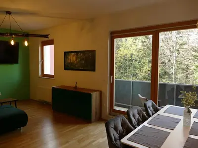 a living room with a table and chairs and a large window at Forest Green Pohorje Apartment in Pohorje