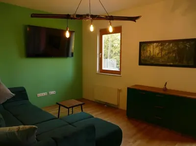 a living room with a blue couch and a window at Forest Green Pohorje Apartment in Pohorje