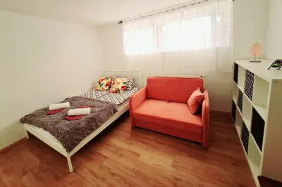 a small bedroom with a bed and a red chair at Apartma Juli in Žirovnica