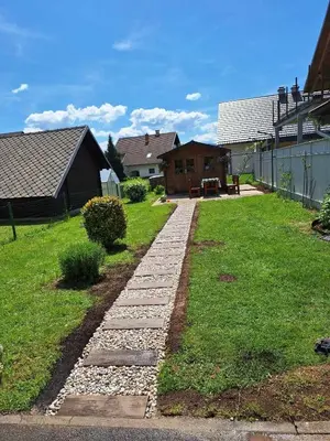 a garden with a stone walkway next to a house at Apartma Juli in Žirovnica