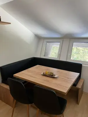 a dining room with a wooden table and two windows at Apartma GABER 125 - Rogla in Zreče