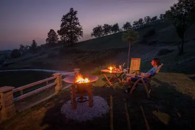 a man sitting in a chair next to a table with fires at Holiday home in Trebelno - Dolenjska & Bela krajina Unter- & Weißkrain 26032 in Trebelno