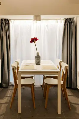 a white table with a vase with a red flower on it at Vila Jakopič apartments in Ljubljana