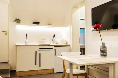 a kitchen with white cabinets and a table with a flower in a vase at Vila Jakopič apartments in Ljubljana