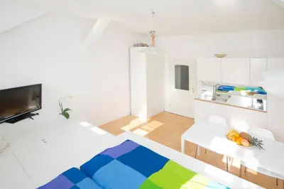 a white living room with a couch and a kitchen at The cute, sunny apartment in the center +P in Ljubljana