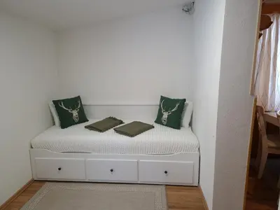 a white bed with green pillows on top of it at Triglav Cottage in Bohinj