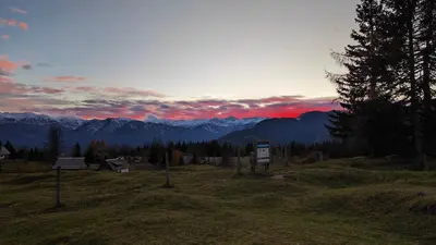 a sunset in the mountains with a sign in a field at Triglav Cottage in Bohinj