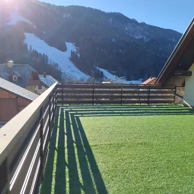 a fence on the side of a house with a mountain at Apartmaji Biseri in Kranjska Gora
