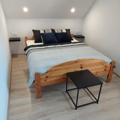 a bedroom with a large wooden bed and a table at Apartmaji Biseri in Kranjska Gora