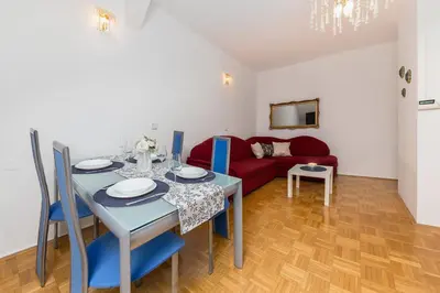 a dining room with a table and a red couch at Apartma Lea in Slovenj Gradec