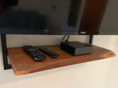 two remote controls sitting on a wooden shelf under a television at Apartment House Prezlc in Kranjska Gora