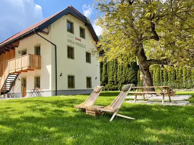 two chairs in the grass in front of a building at Apartment House Prezlc in Kranjska Gora