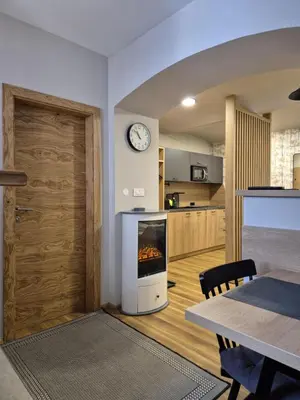 a living room with a fireplace and a clock on the wall at House Godec - Rateče Planica in Kranjska Gora