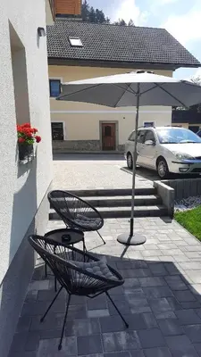 a patio with two chairs and an umbrella at House Godec - Rateče Planica in Kranjska Gora