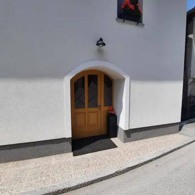 a door in a white building with a flower next to it at House Godec - Rateče Planica in Kranjska Gora