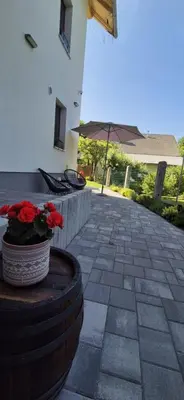 a patio with a pot of red flowers and an umbrella at House Godec - Rateče Planica in Kranjska Gora