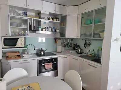a kitchen with white cabinets and a table with chairs at Apartma Modro gnezdo in Kranjska Gora