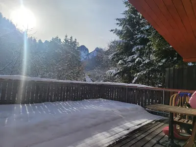 a snow covered deck with the sun in the background at Apartma Modro gnezdo in Kranjska Gora