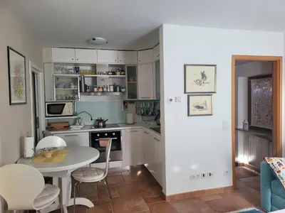 a kitchen with white cabinets and a table and chairs at Apartma Modro gnezdo in Kranjska Gora