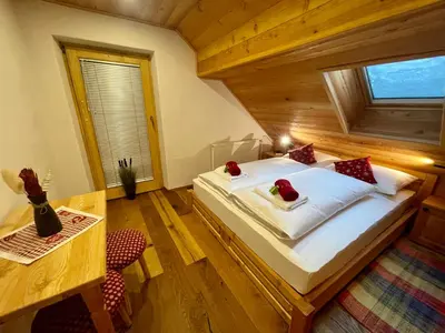 a bedroom with a bed and a table and a window at Hotel ŠURC in Kranjska Gora